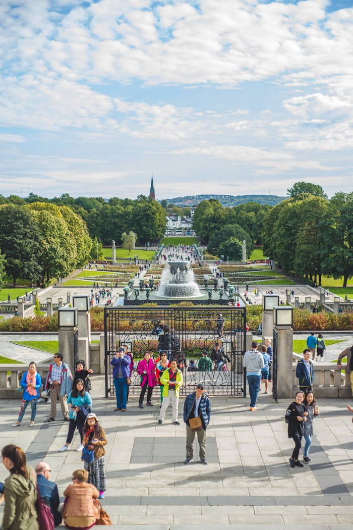 journey People enjoying a sunny day at Vigeland Park in Oslo, Norway, surrounded by lush greenery and fountains.